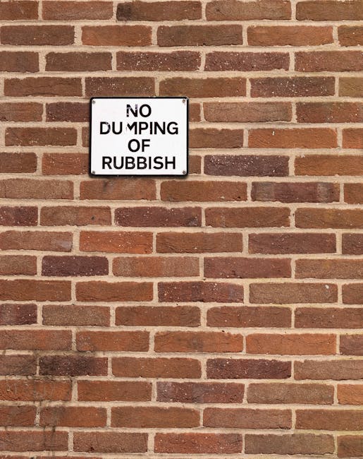 A close-up view of a pale green or light grey wall panel, featuring a black, three-dimensional sign that reads 'trash here' with a downward-pointing arrow. The sign is mounted on the wall, with the te